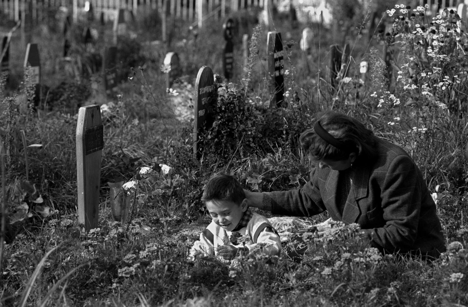At the risk of getting killed by sniper fire a mother comforts her son as they visit the grave of a loved one. During the war in the former...