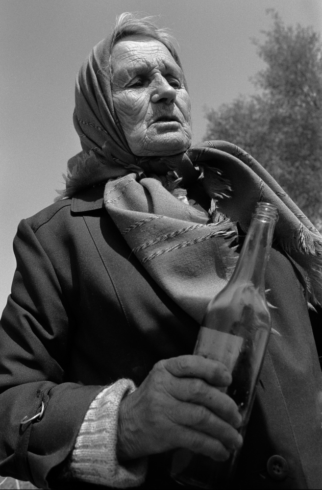 Russia - The Village of Anufrievo - A woman prepares to pour vodka to honor the dead. Each...