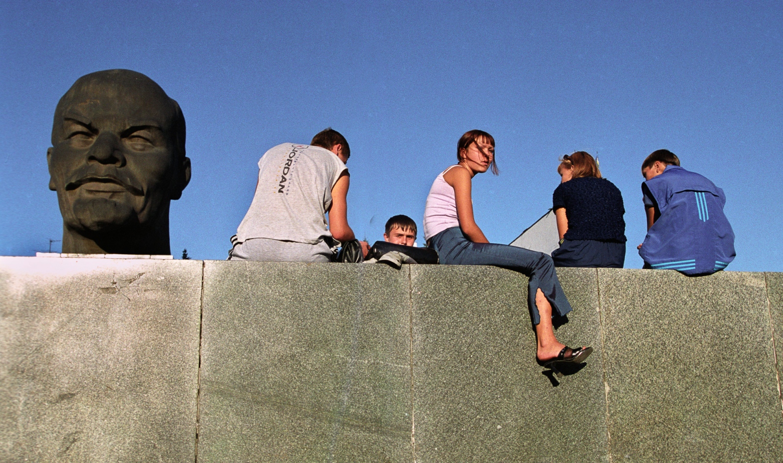 Russia In Transition - 1990s - The bust of Lenin looms over teenagers hanging out at the...