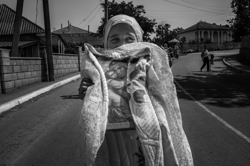 Young girl carrying an image of _gin Mary at a funeral in Moldova