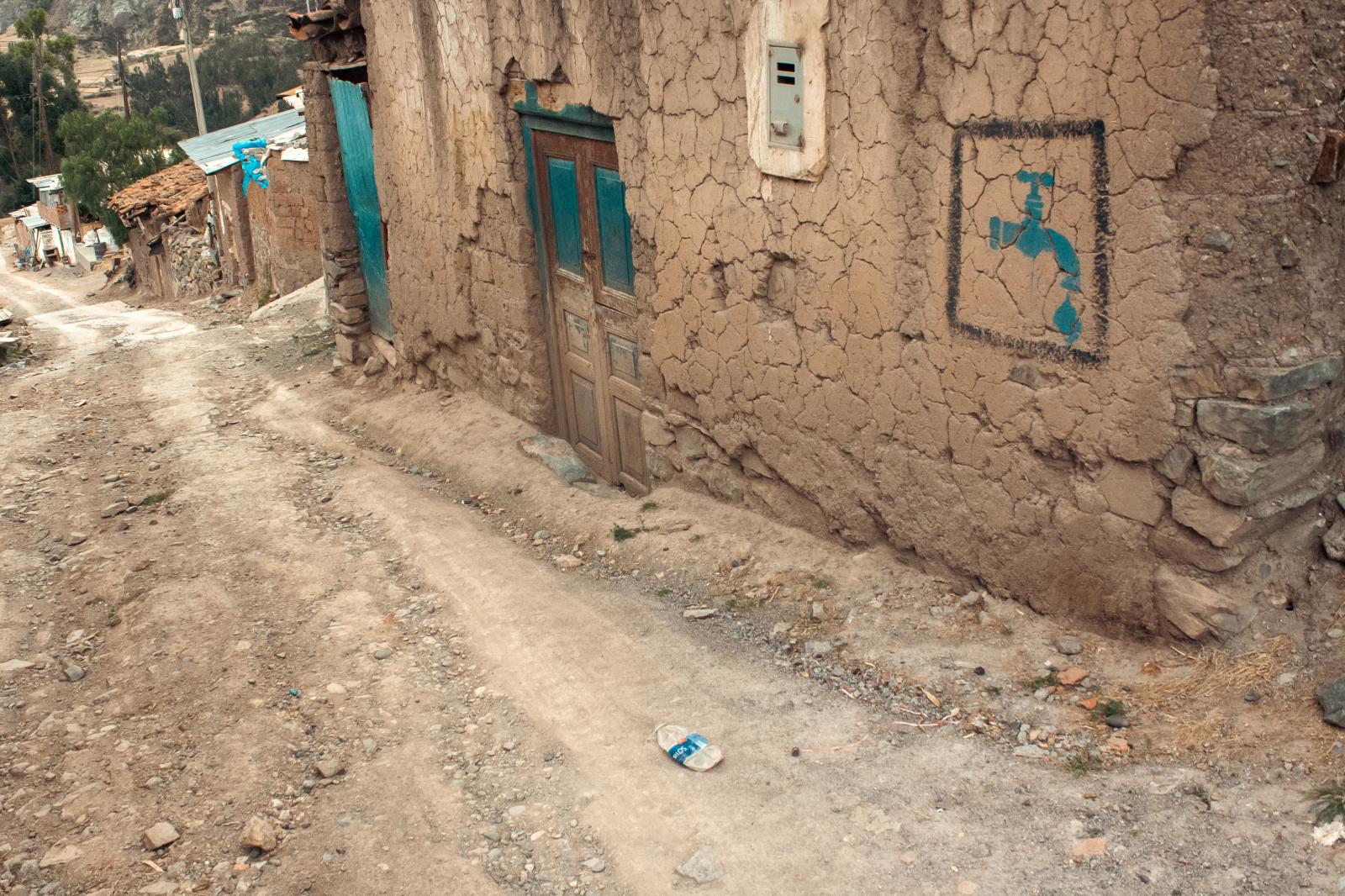 Drought -  A dirt road near Huaraz cuts through highland villages, where a painted water symbol marks the...