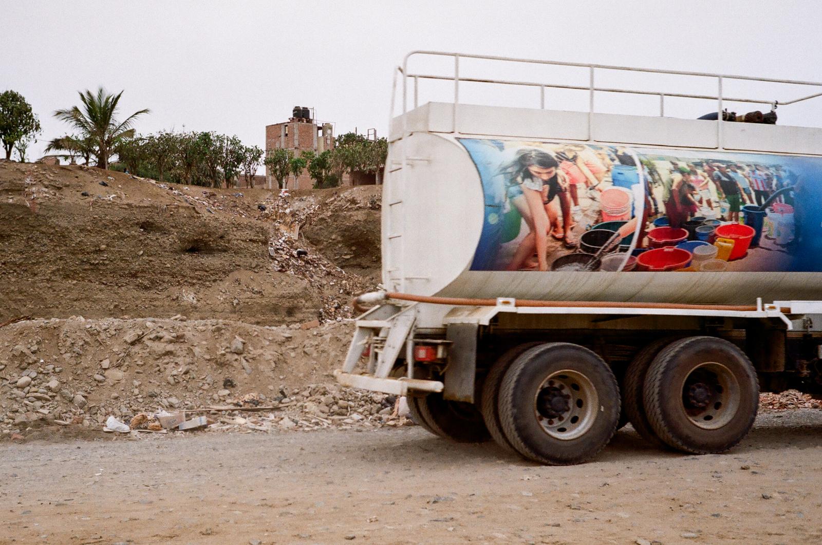 Drought -  A water truck drives along a dirt road in northern Peru, its side displaying images of locals...