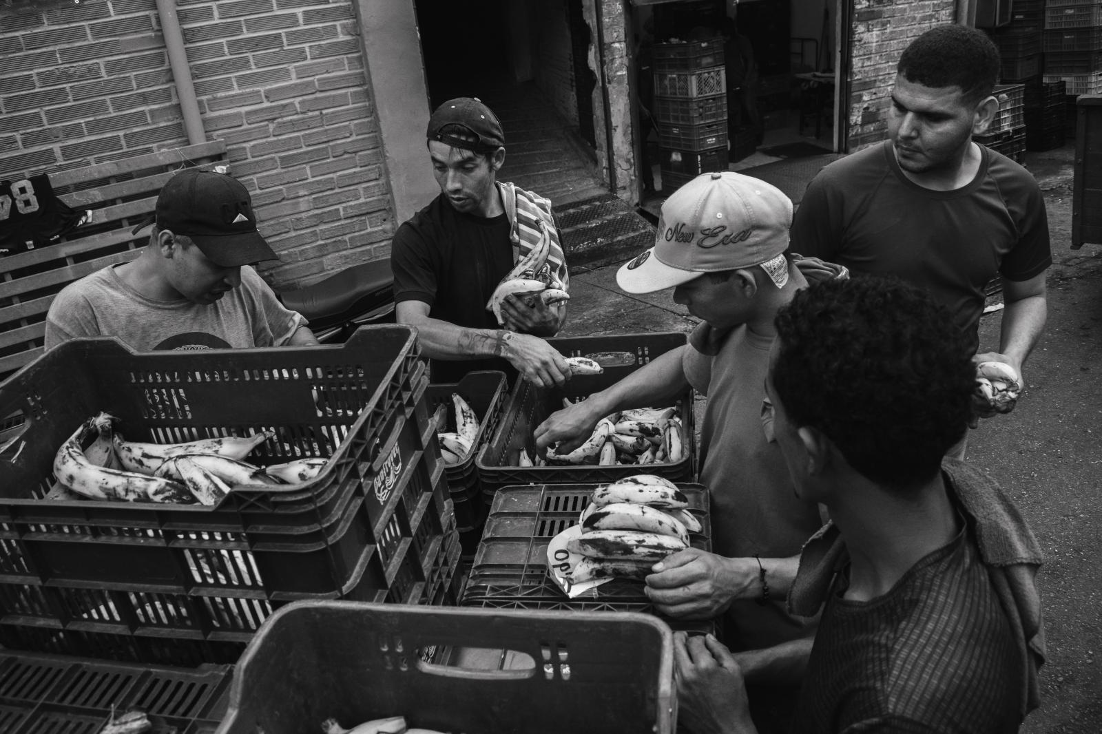 Carga: The Weight They Carry -  Overripe bananas destined for trash become a shared meal at day’s end - a small moment of relief...