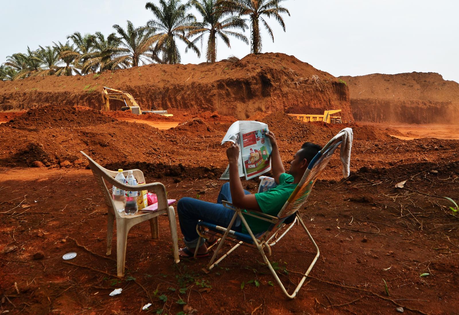 A man reads the newspaper while...Photo) Felda Bukit Goh malaysia