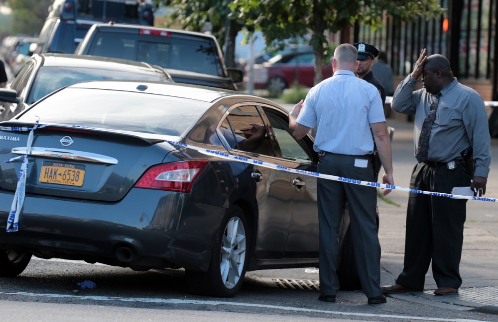   A seasoned NYPD detective (R) from the 114th Precinct in Astoria, Queens react to a shooting evidence inside a Nissan Maxima at 28th Ave and Steinway Street early Sunday morning.&nbsp;  