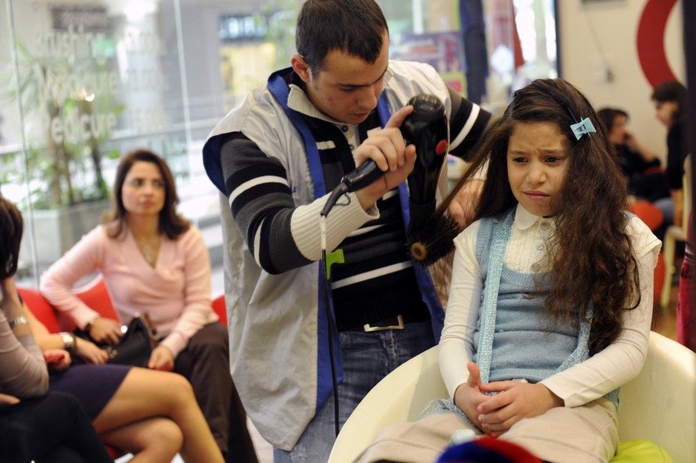 Kteer Jeune (Very Young) - A young girl has her hair straightened at an...