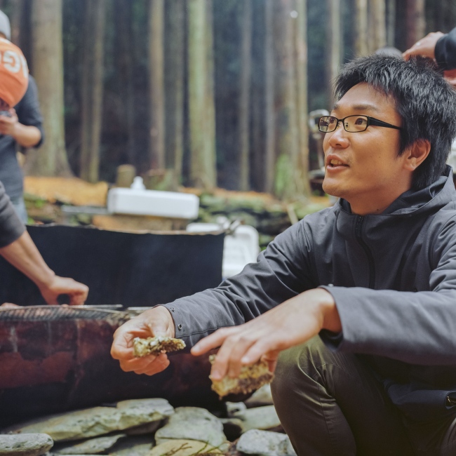 Kameyama Sensei (meaning teacher and in this case used as a title of respect) pauses during a team lucheon around a grill in the camp grounds of Hamagurihama. The project is working to develop a number of programs including camping and nature studies.