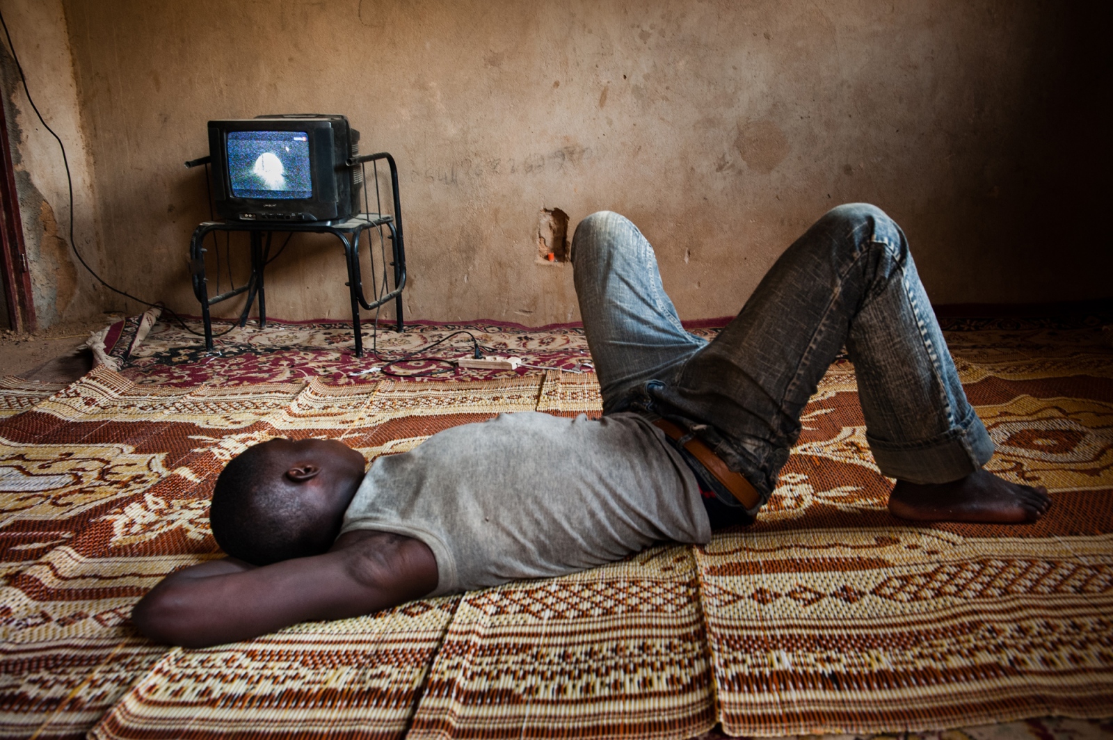AFRICA. EXODUS.  PART 1 - Niger. Agadez. A young African migrant is killing time by...