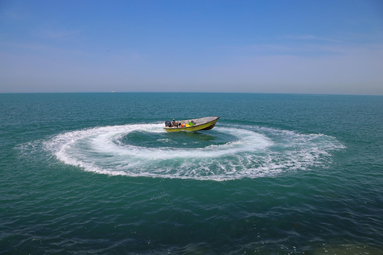 A boat is sailing on the northe...rthwest shoreline. Bushehr Iran