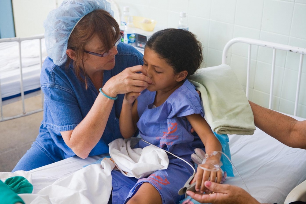 Medical Missions - Ann Bennett-Collazuol, RN gives sips of water to Raysa...