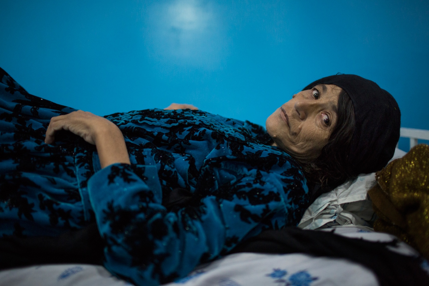  Jummaghul rests in one of the private rooms at the hospital. In the past, Jammaghul was often beaten by her husband, especially on her head, which her sister believes led to health problems. Jammaghul divorced her husband about 10 years ago, but she rarely sees any of her 5 children, which causes her great distress. She now lives with her brother, who brought her to the hospital. Mazar e Sharif, Afghanistan. December 2015. 