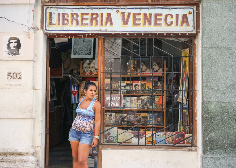 Cuba -       Woman standing in the door of a bookstore Havana,...