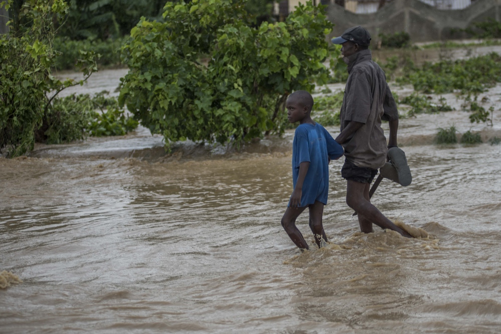 A man with his son are crossing the flood river of LéogÃ¢ne 