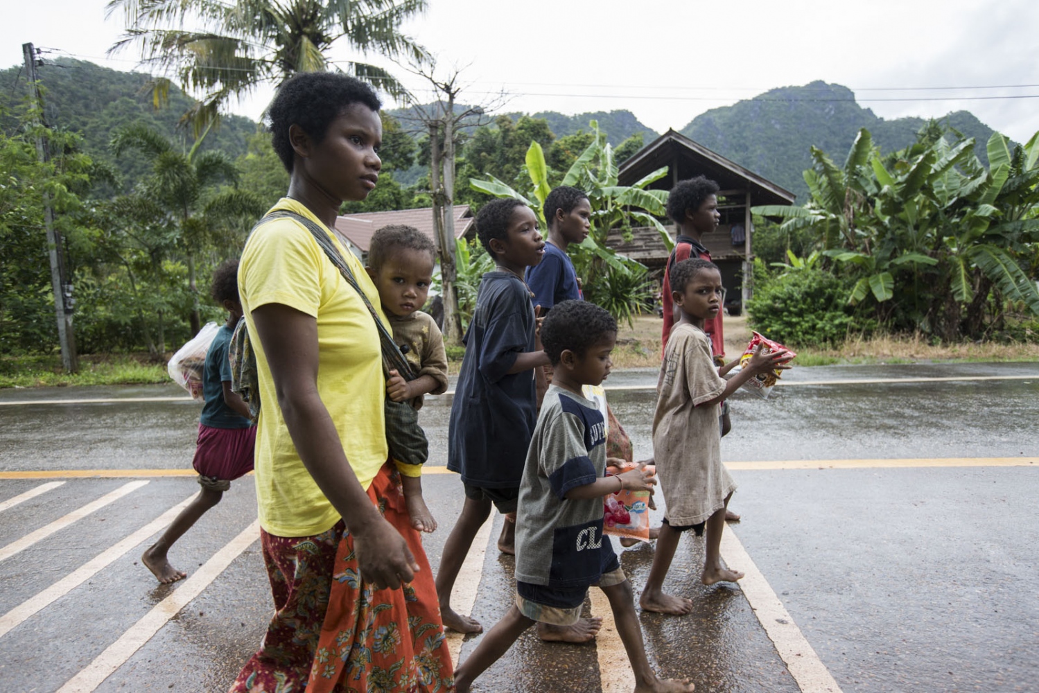 THE MANIQ - A group of Maniq youngsters walk bare-footed along a road...