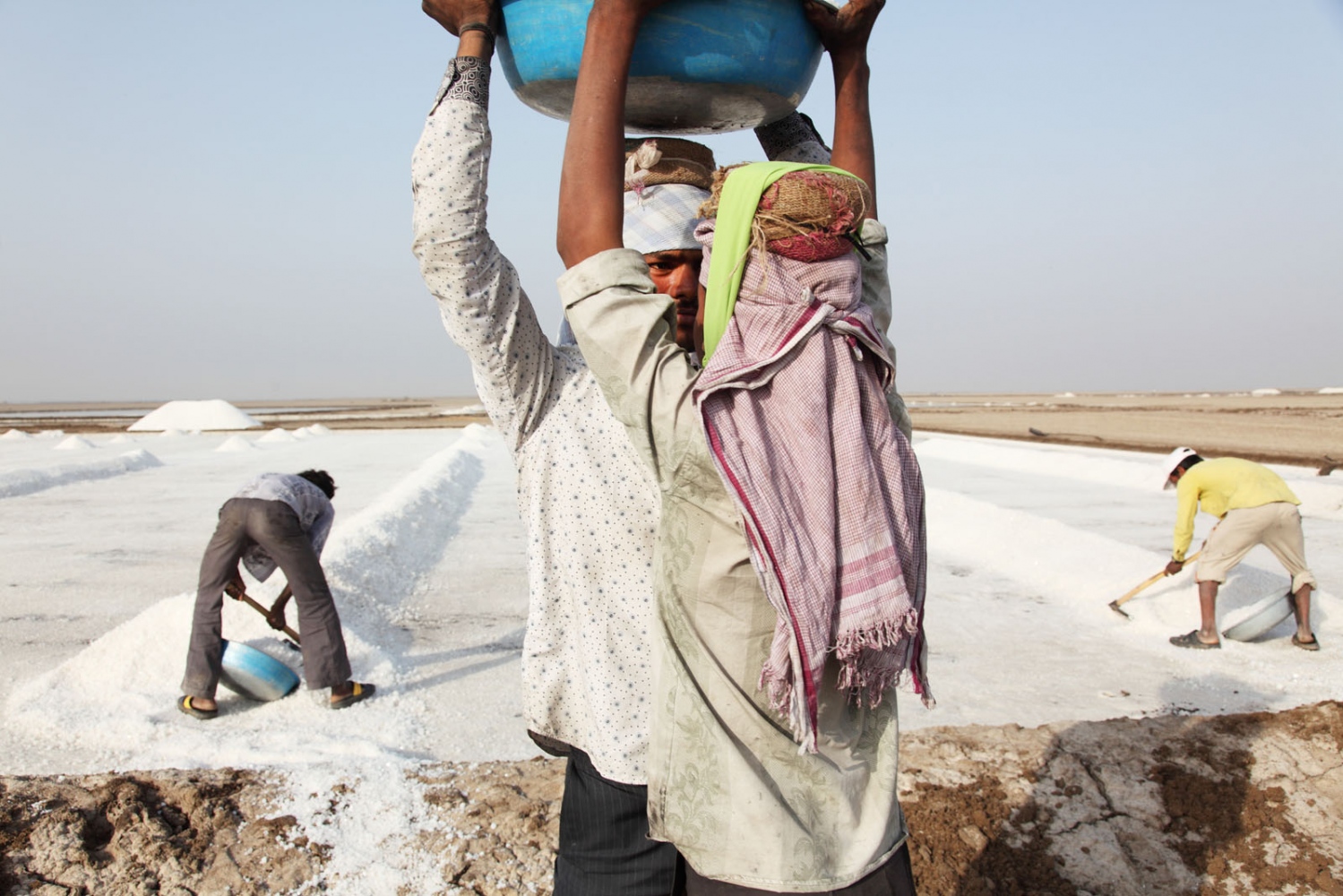 SALT - Salt workers collect freshly made salt from large pans on...