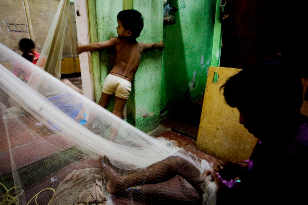 A boy plays as the men prepare net for next dayâ€™s fishing.