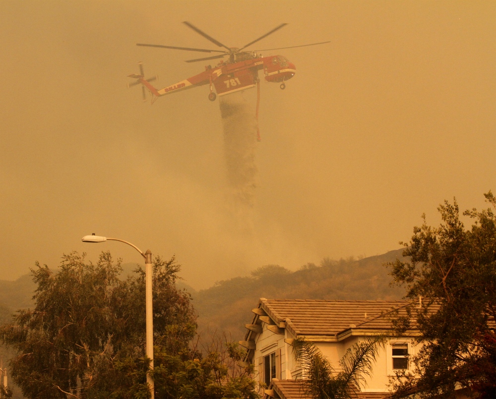 A helicopter drops water on the... 18 homes were lost or damaged.