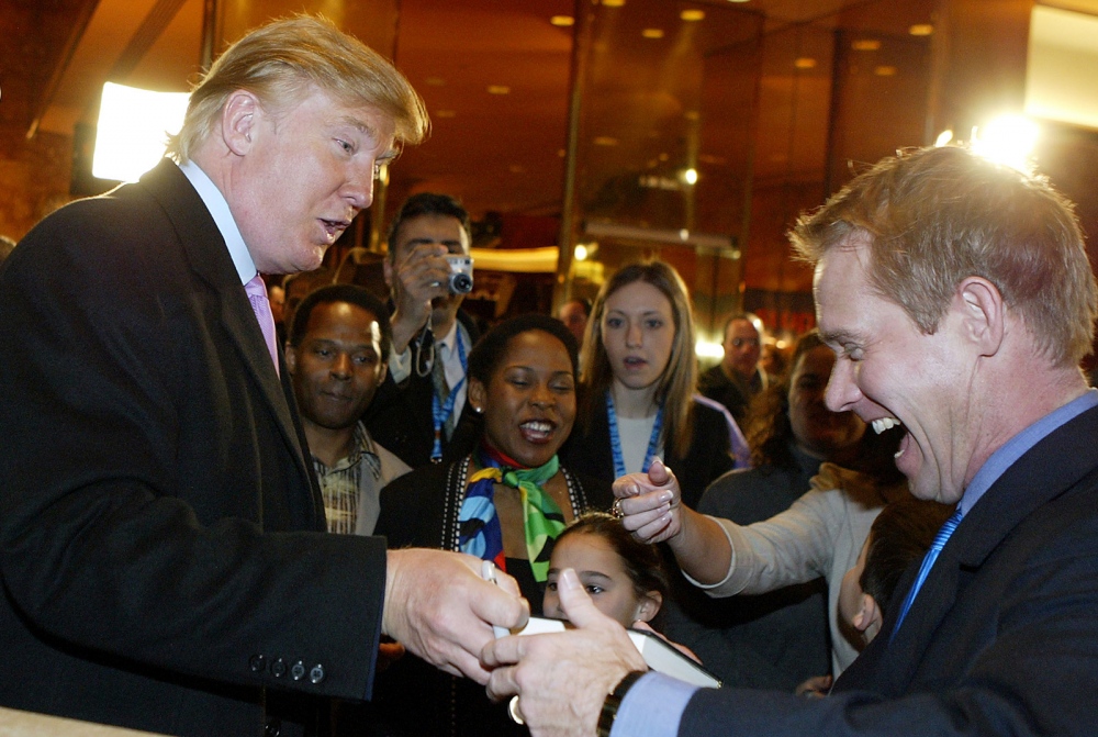   President Donald Trump signs a book to an unidentified supporter in New York.  