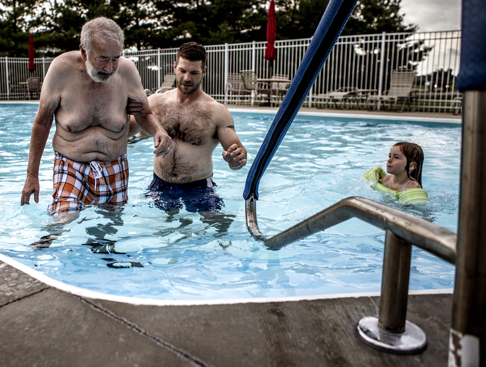 Sandwiched In - Morgan helps his dad wade through the pool while his...