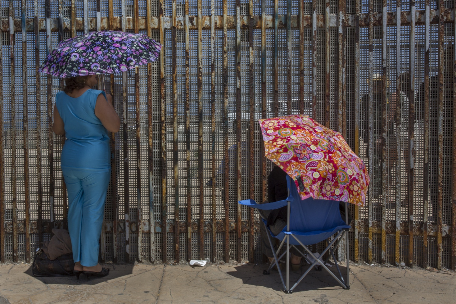 The Wall -  Two women meet with family members under the July sun at...