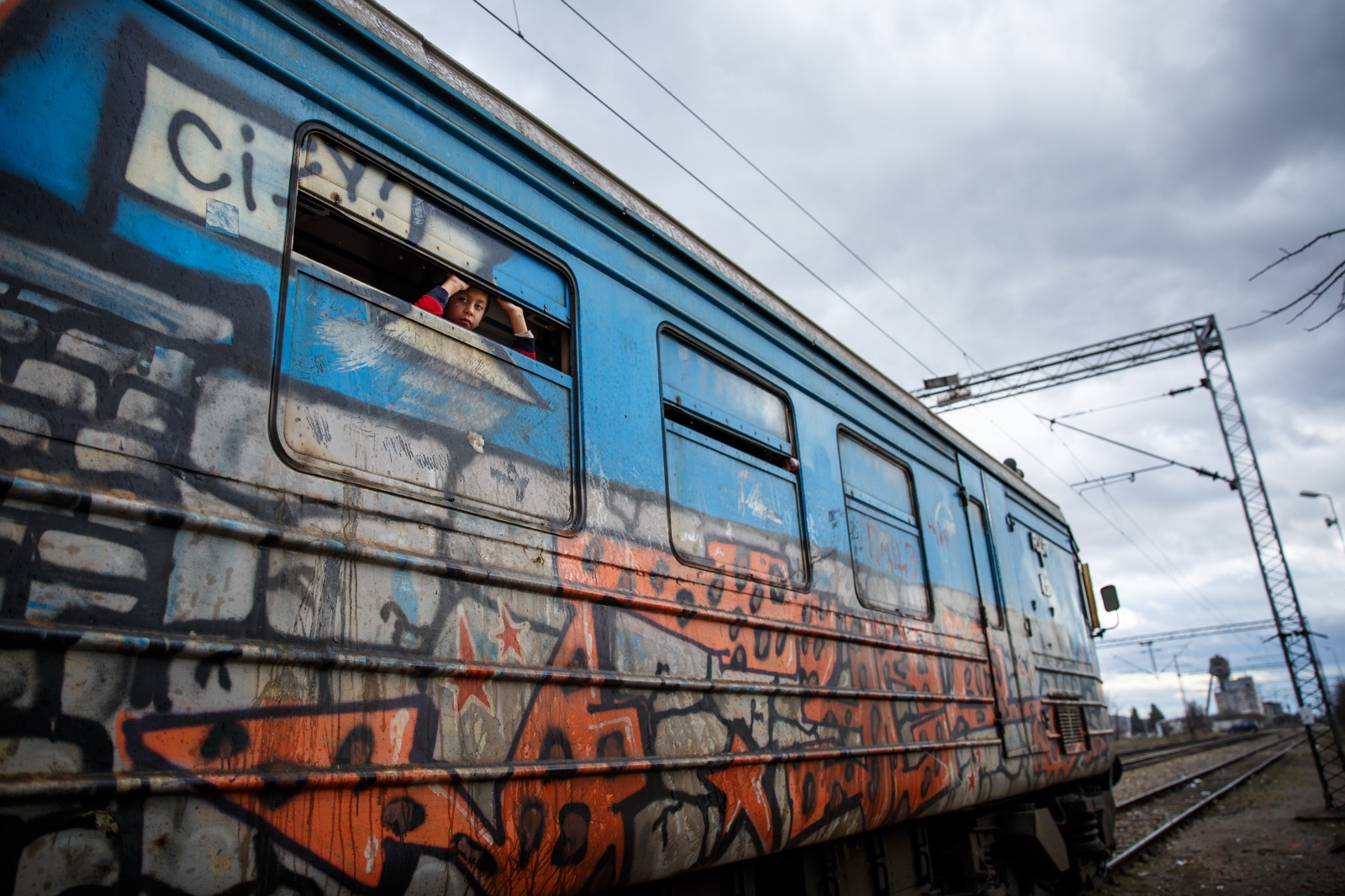  A young refugee peaks out his window as the train departs Presevo, Serbia for the Croatian-Serbian border, January 2016. 