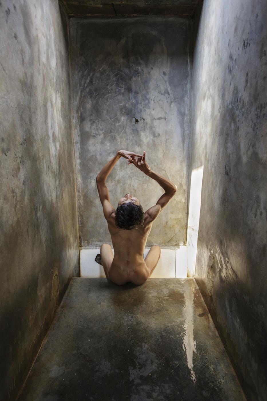 Disorder - 2012_A man sings in his cell, his hands moving in an...