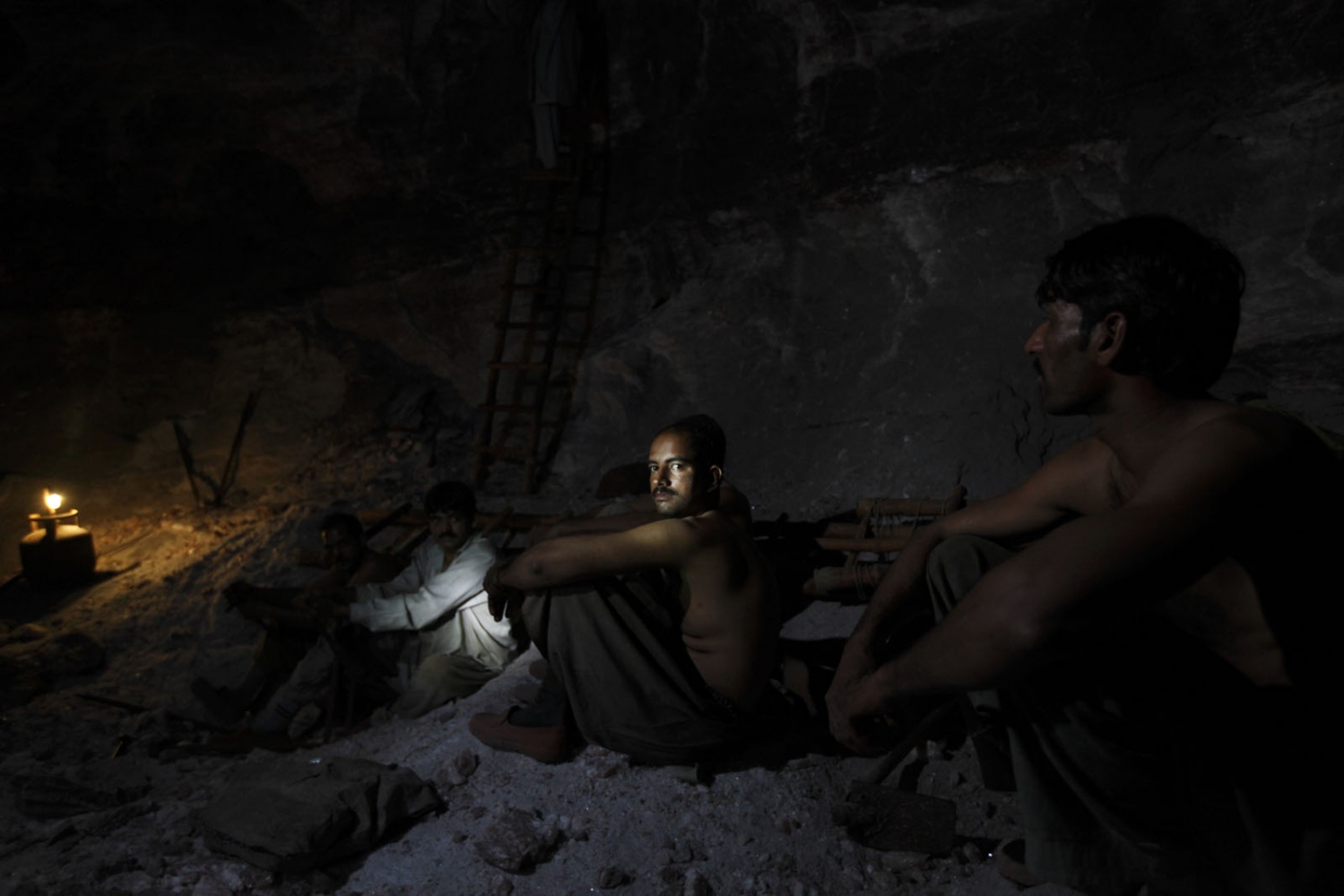 PAKISTAN'S SALT MINES -  A group of salt miners take a rest inside the dark...