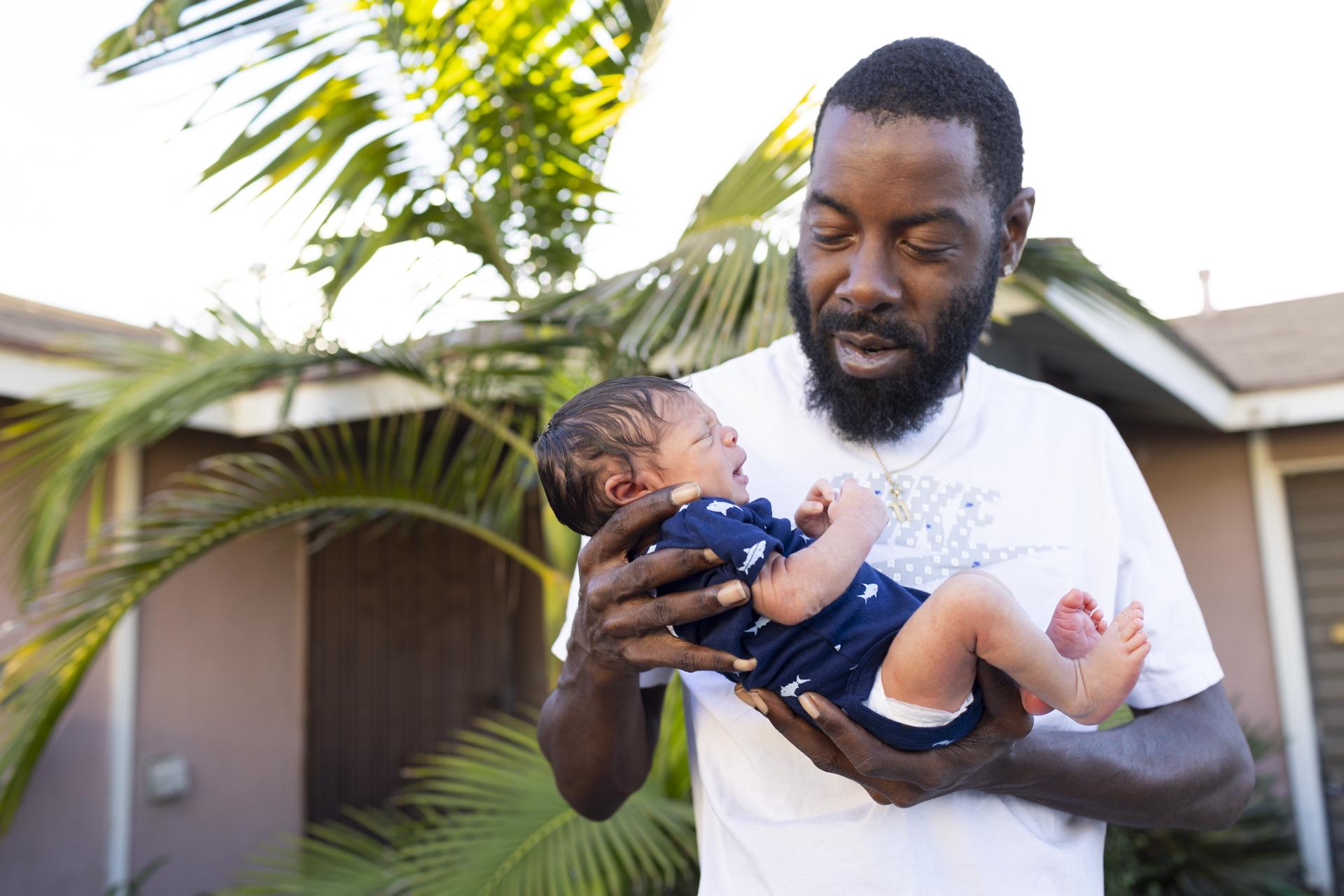 Robert Wood Johnson Foundation - Chris Johnson holds his 1 week old baby Noah in front of...