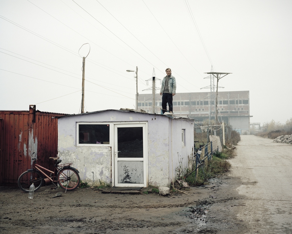 Romania, Giurgiu. A man working as security guard stand on a barrack in front of an abandoned...