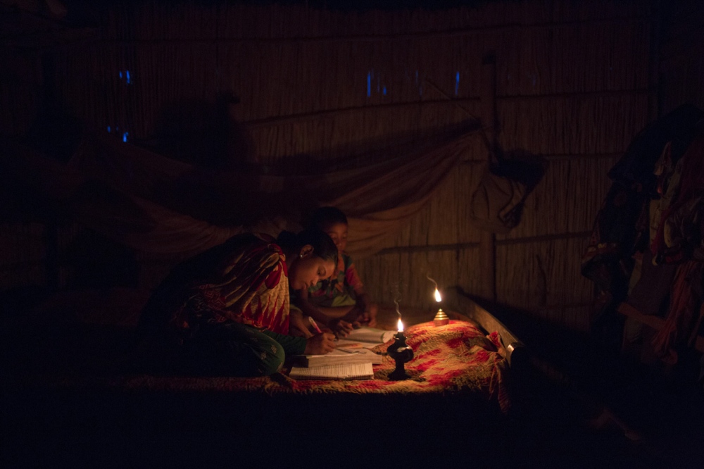 In a house Eity Rani, 14, and Shobo Rai, 8, do their homework by the light of an oil lamp. Life is much harder for children who were born in to enclaves. To go to school their parents must pay money under the table and receive a fake address. Debiganj, Bangladesh