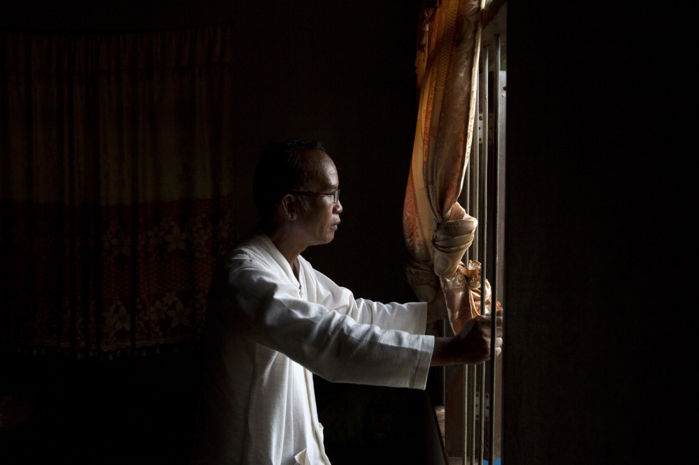 Image from NGO/DEVELOPMENT - Por Sakmi looks out of a house in his village of Na Nong...