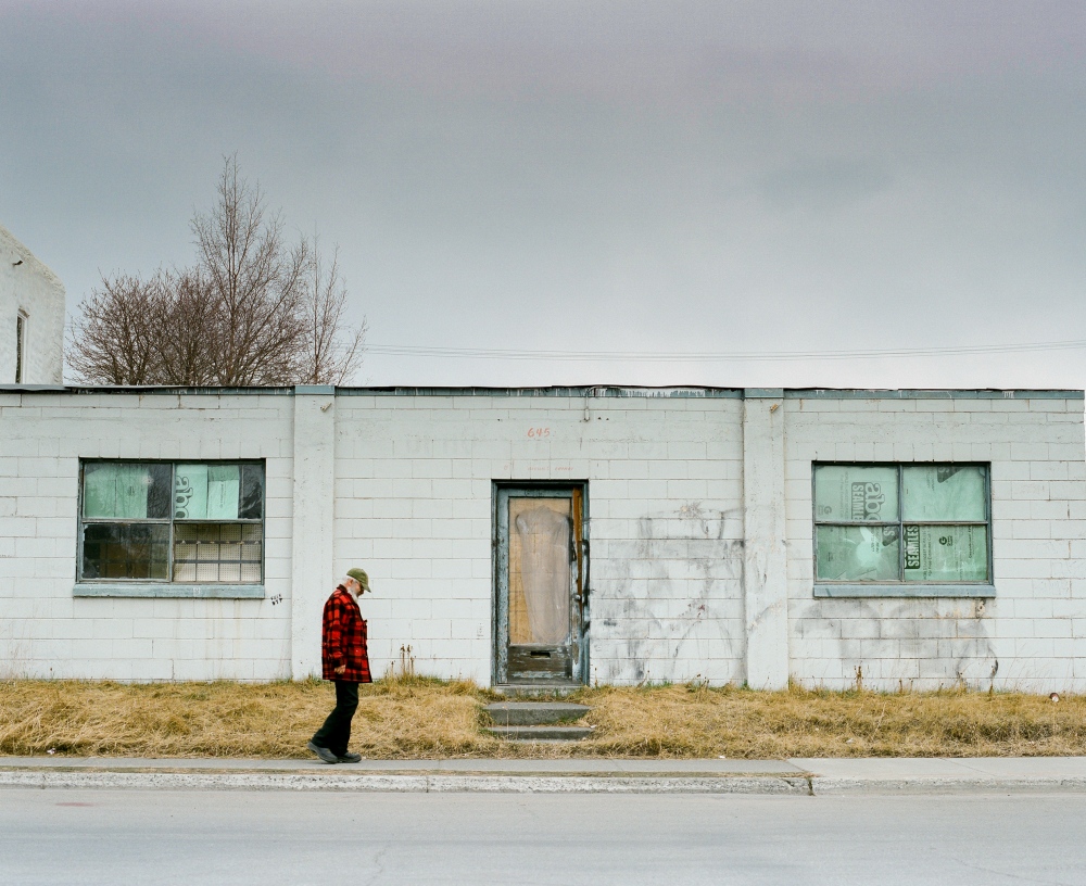 Image from CALL HER ALASKA - A man walks by a building in the neighborhood of Fairview...