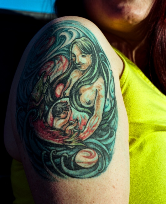 Hannah Heimbuch, 31, shows a tattoo of one of Bristol Bay's salmon-inspired Apayo Moore's paintings. Heimbuch is a commercial fisherman who is involved at the organizational level in the fishing community and just bought her first boat of her own with her brother.