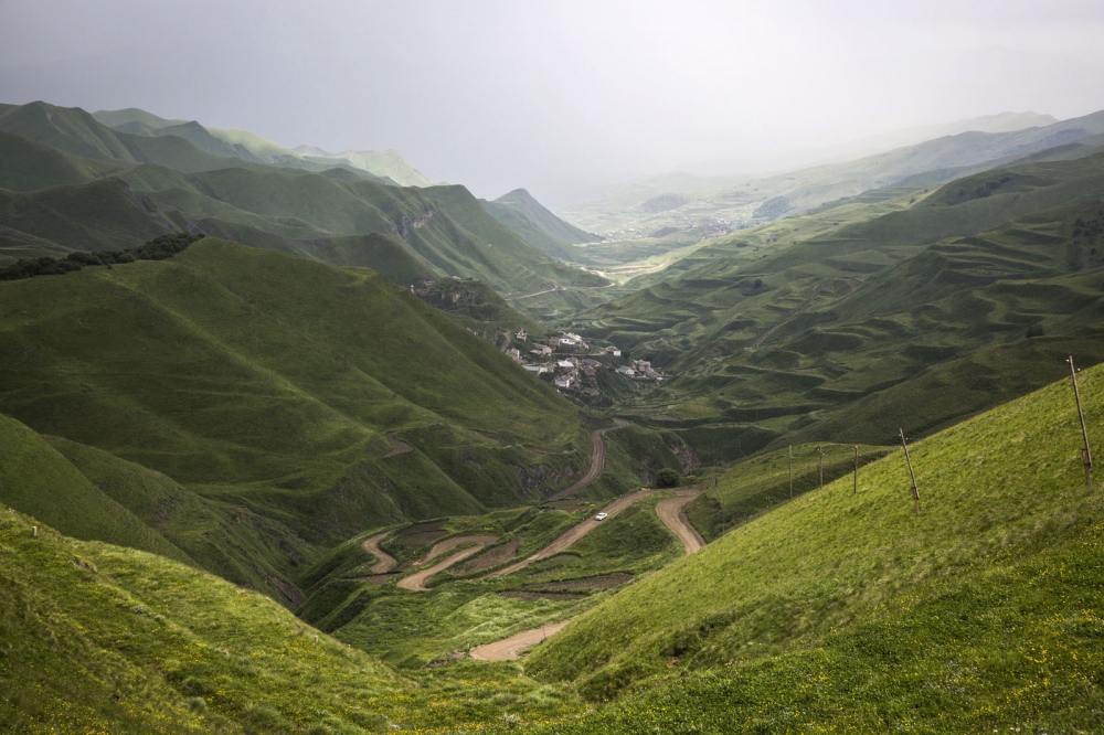 A remote twisty road winds its way through the green hills as rain approaches in the little known Republic of Dagestan, Russia.