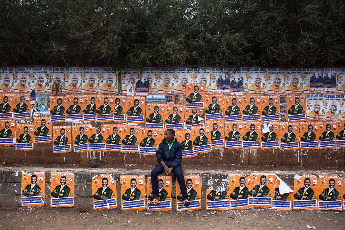 Baba Odinga -  Boy sitting in front of a wall covered by electoral...