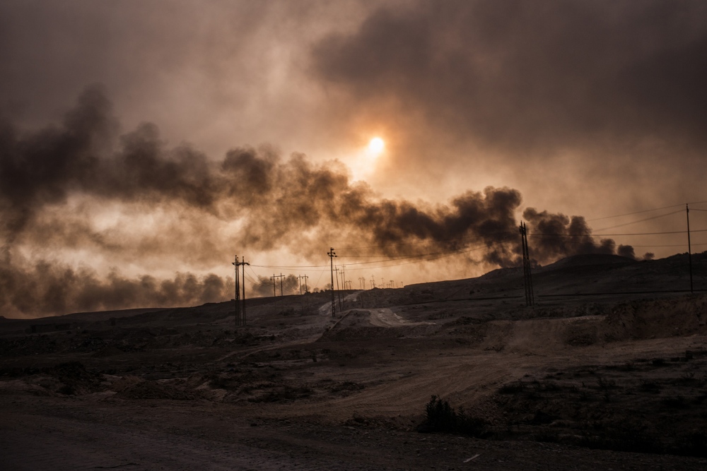 Oil wells burn in Qayyarah, Ira... clouds hanging over the town. 