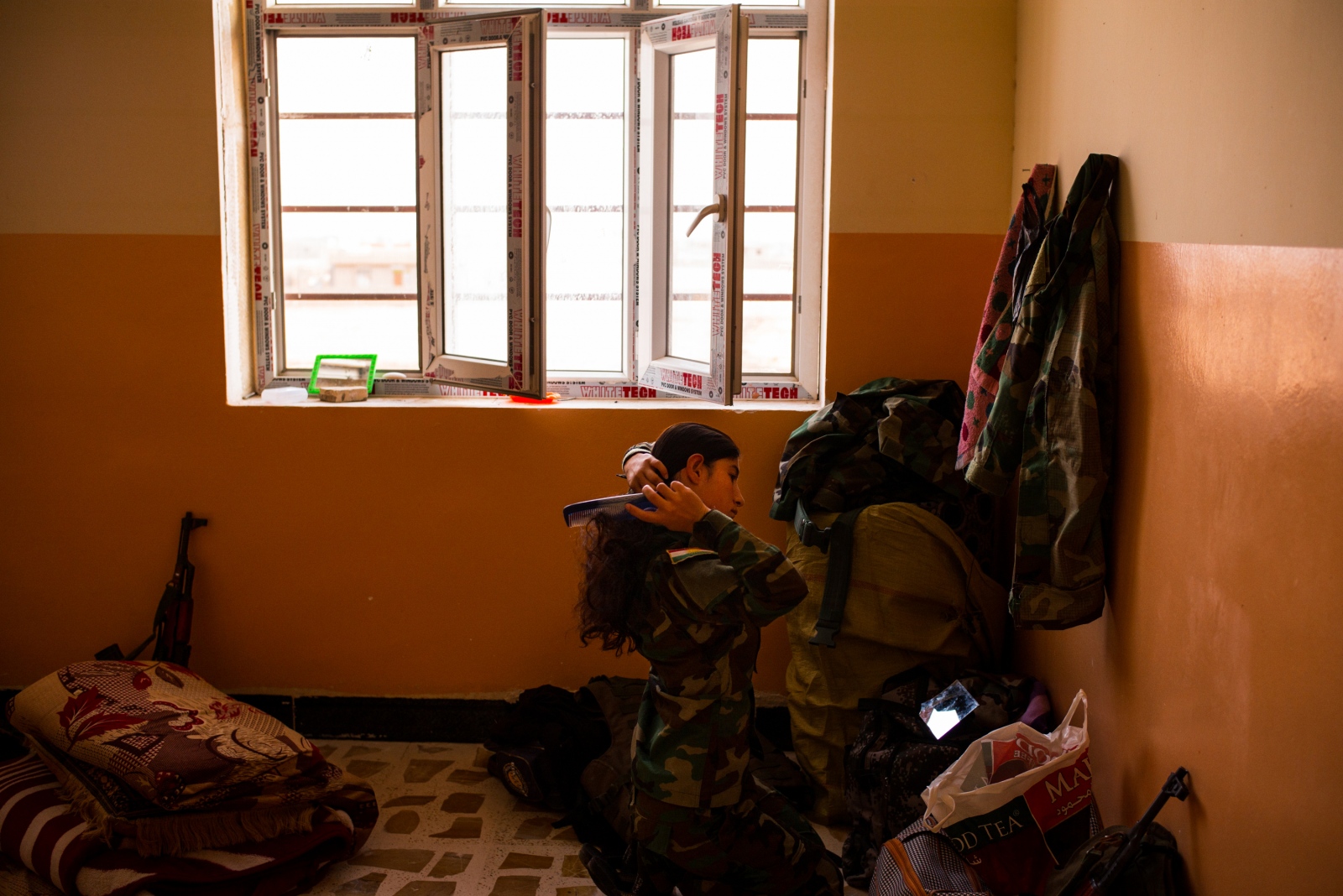 A soldier with the Yazidi 'Sun Ladies' brushes her hair during morning preparations at...