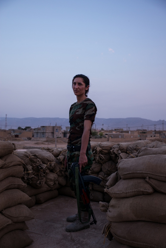 A soldier with the Yazidi 'Sun Ladies' battalion stands on guard duty at their base...