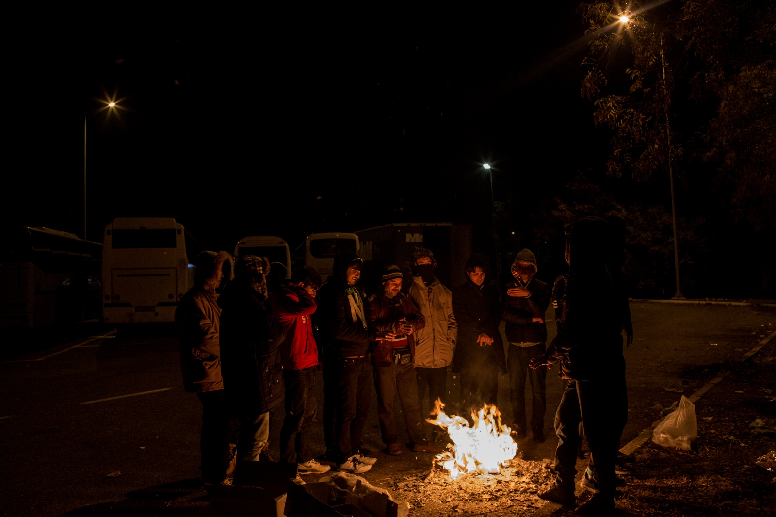 Refugees warm themselves by a self-made fire during another long stop at a roadside pit-stop on...