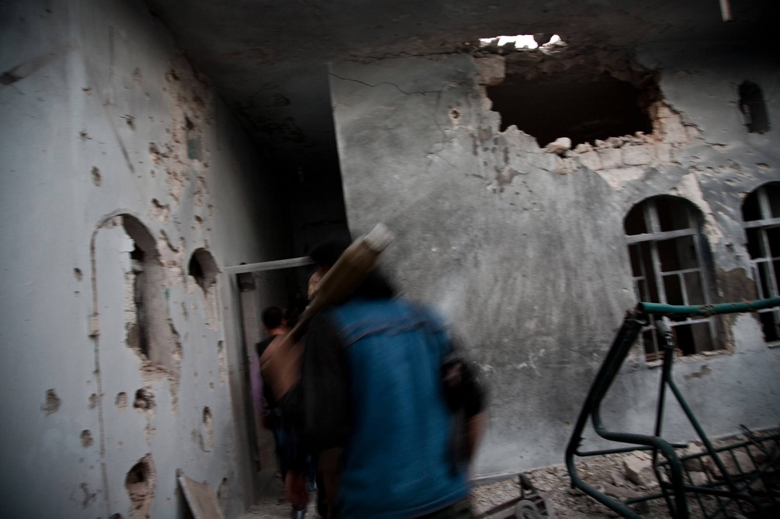 A fighter with the Free Syrian Army walks through heavily damaged buildings in the Karm Jebel...