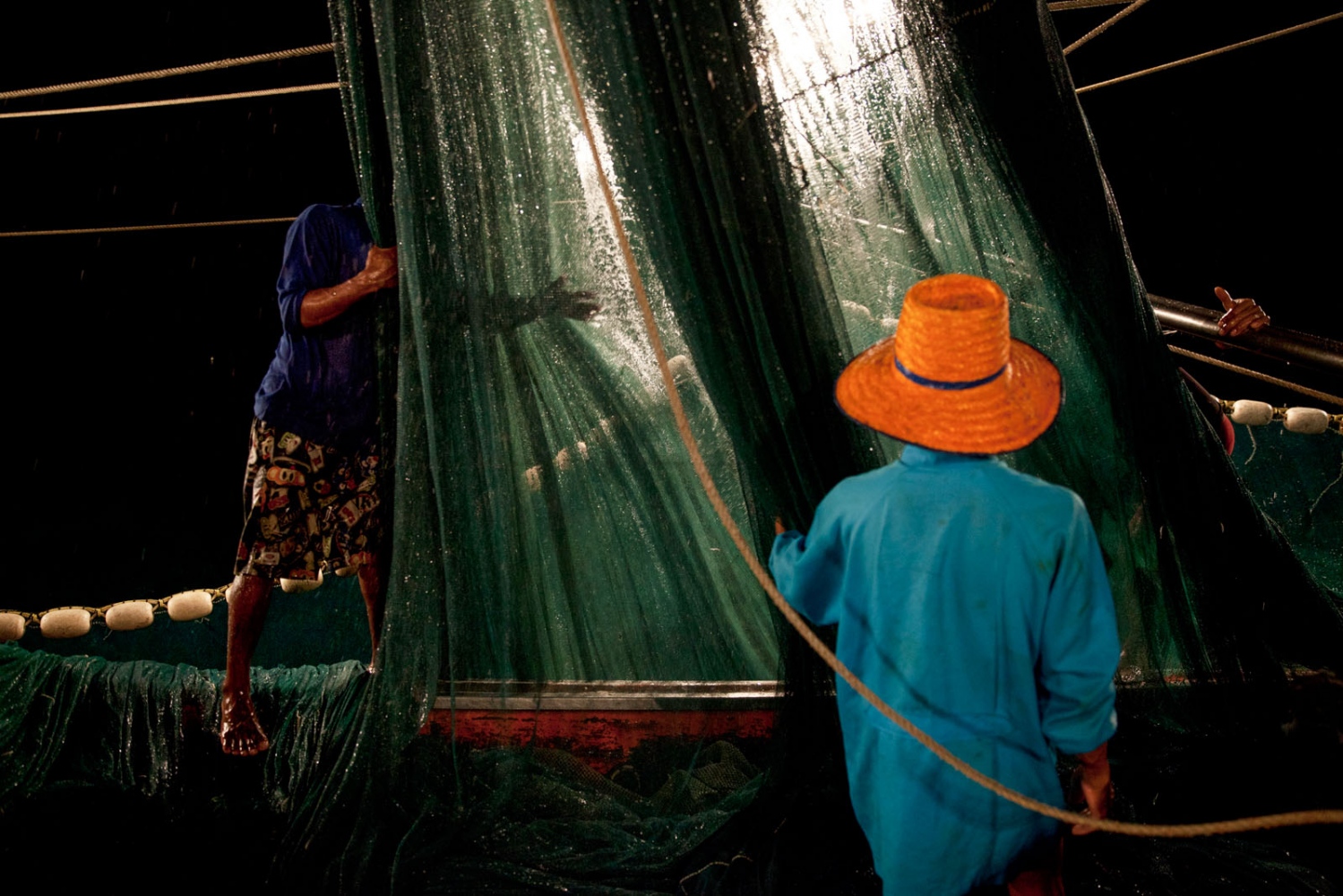EMPTYING THE SEAS - Burmese fishermen working all night on a Thai fishing...