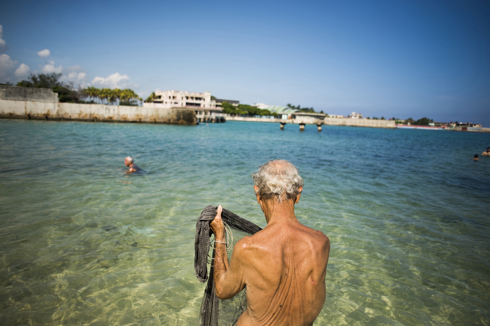 Â¡Cuba Libre! - A man fishes with an old, traditional fishing net behind...