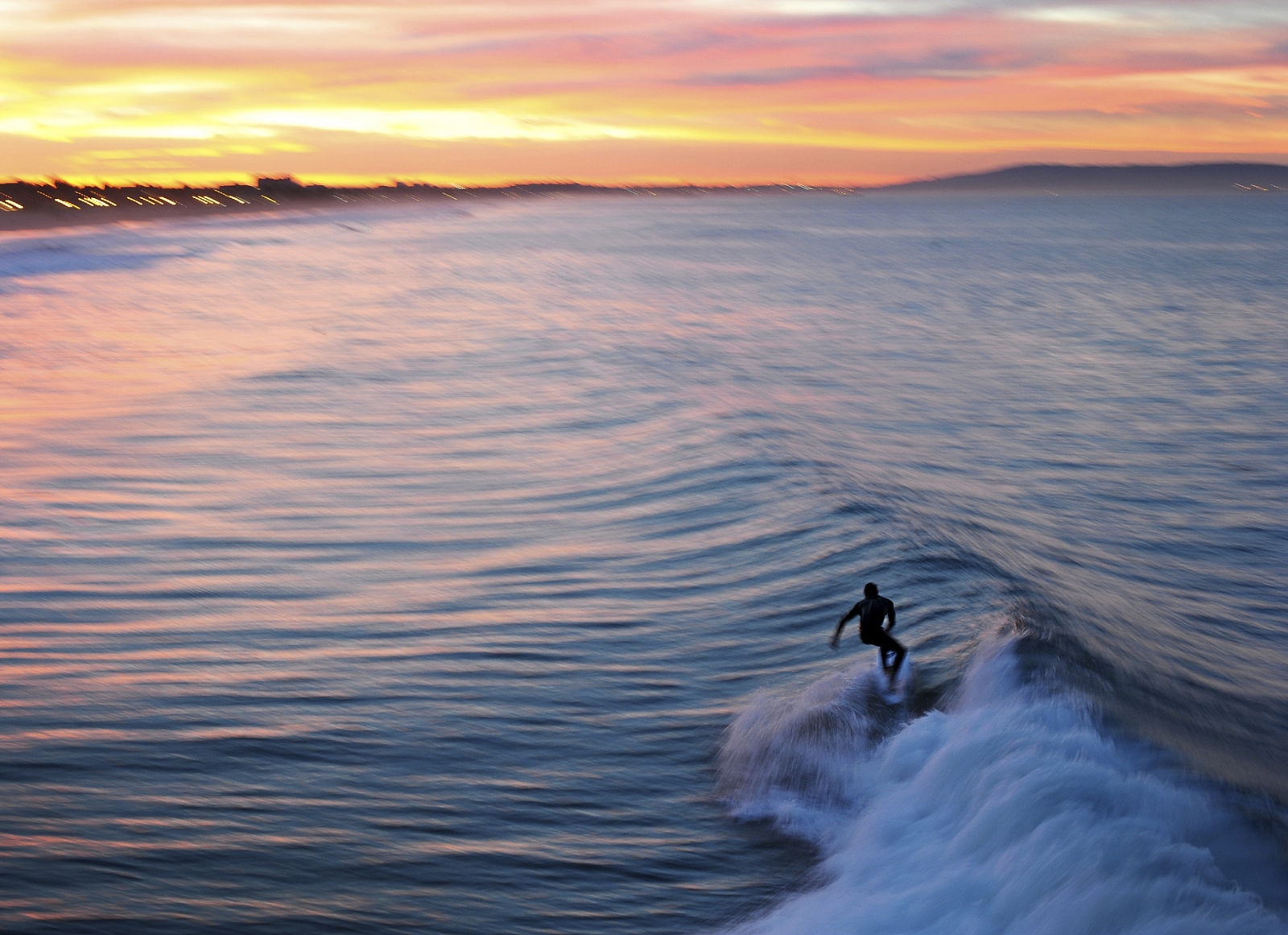 A surfer catches a wave in the early morning near the Santa Monica Pier in December 2016.