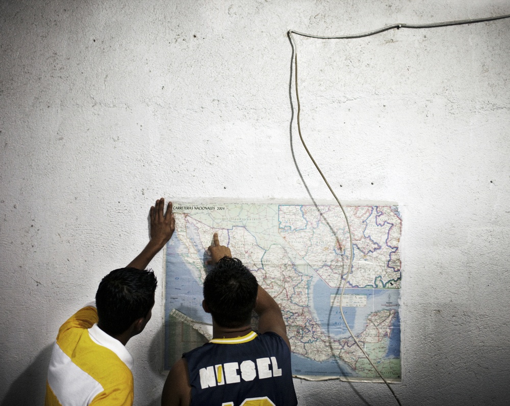 Two migrants check a map at a m...America cross Mexico each year.