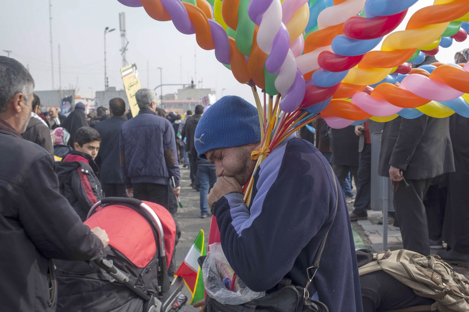 A man sells balloons in the dem...ming poor and poorer every day.