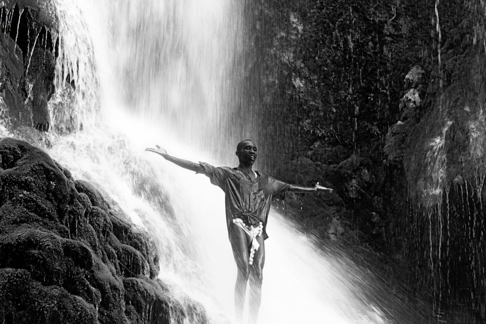 A man basks in sacred waterfalls during a Vodou pilgrimage.