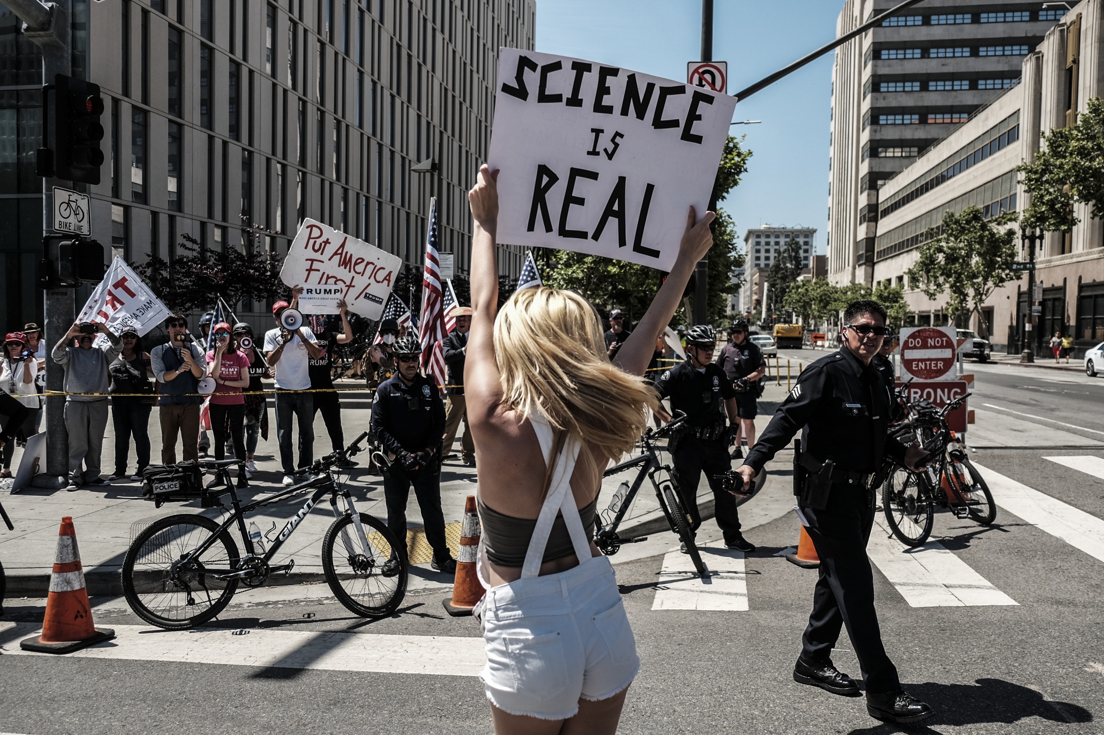 A woman is seen demonstrating in front of a small pro-Trump counter demonstration as scientists...