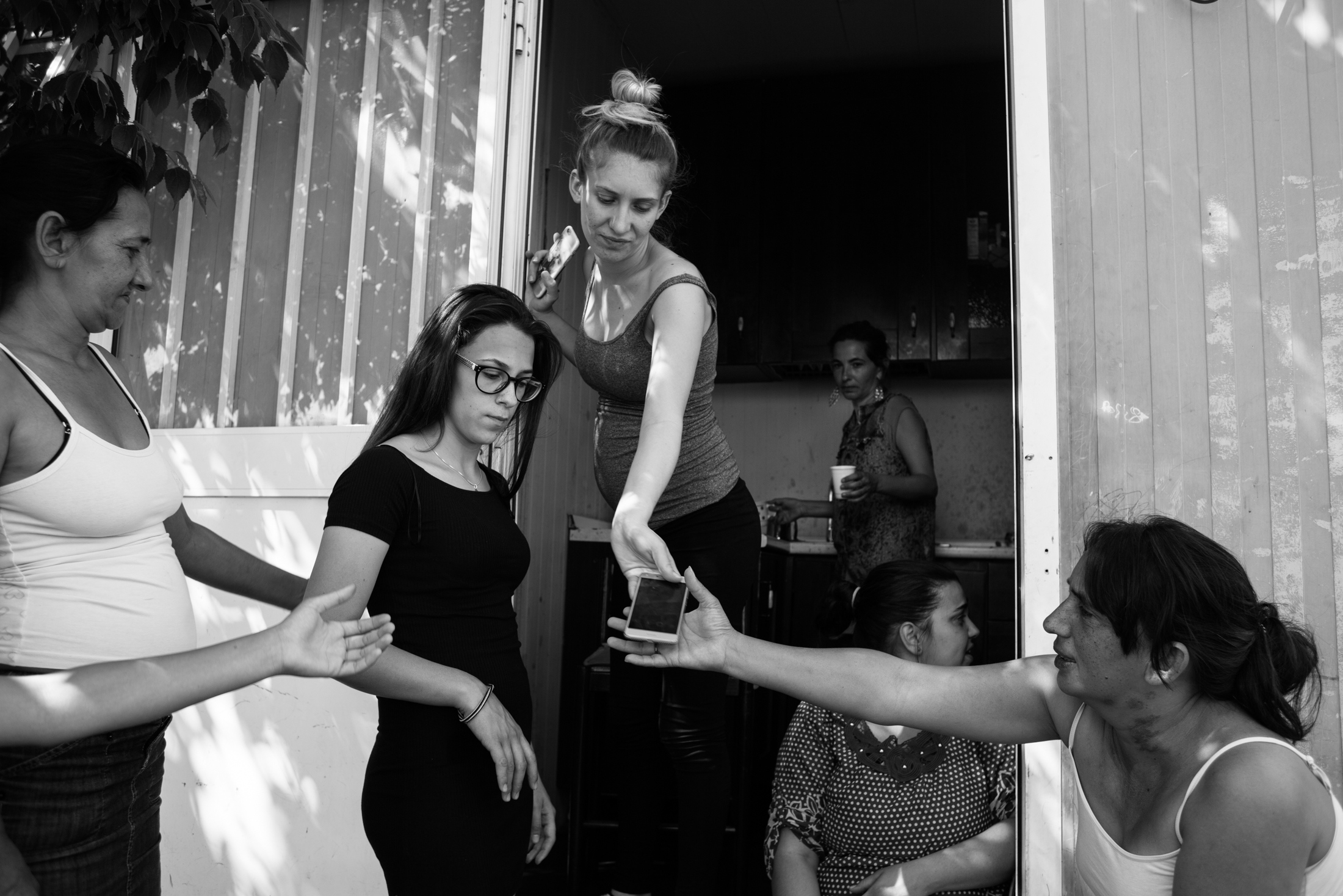 May 2017, nomad camp of Castelnuovo Rangone, Emilia Romagna, Italy. The women of different families exchange a smartphone to watch a news on the internet. Not everyone has a cell phone in the camp, and those who share it with the whole community.