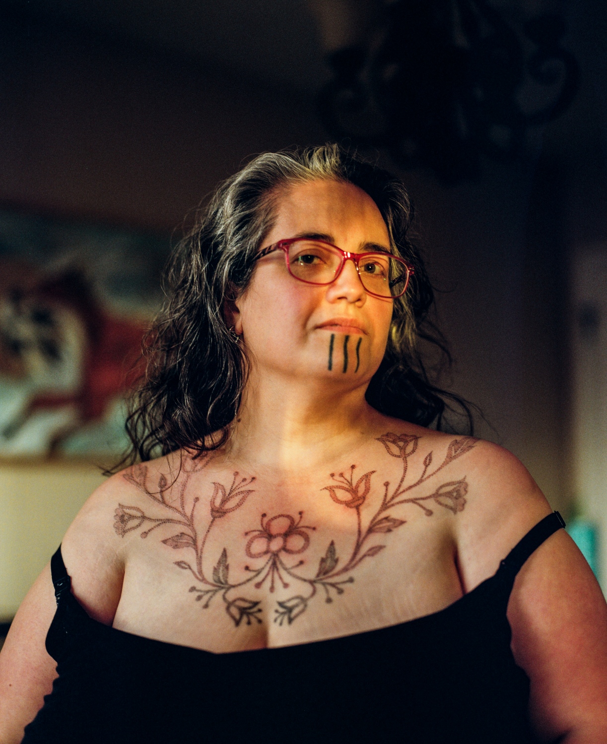  Grete Chythlook 42, in Sarah Whalen-Lunn&#39;s home in Anchorage, Alaska, after having a chest piece inspired by traditional beadwork done by Whalen-Lunn. Whalen-Lunn had also done Chythlook&#39;s chin tattoo. For Chythlook, that tattoo is both a tangible and also a deeply spiritual thing. She says that before she knew that chin tattoos were a part of her heritage, she was already dreaming of them.&nbsp; &ldquo;I started dreaming about chin tattoos when I was in my late teens and early twenties, and at that time, I didn&rsquo;t know anybody who had a chin tattoo, whether Inuit, Gwich&#39;in or any other group. I didn&rsquo;t know anybody personally. I didn&rsquo;t know that the Gwich&#39;in had this tradition&mdash;I just didn&rsquo;t know about it,&quot; she says. &nbsp;When she first saw a woman with a chin tattoo, she says she was too scared and shy to ask her about it. But then, women began talking about Inuit tattoos and a friend asked her to be there in the room with her while she got hers. &ldquo;Being in the room with her while she was getting these marks was so powerful, I couldn&rsquo;t process it&mdash;it was just so powerful. I came home and I told my husband, &lsquo;this is a part of me. This is real. This is something I can&rsquo;t deny anymore.&rsquo;&rdquo;&nbsp; She says that her decision to get the tattoo is partly tied to its visibility, and that where once this was just a regular part of culture, now, as a revitalization, it&rsquo;s a response to colonization and it&rsquo;s lasting effects. &ldquo;Choosing not to pass was a big factor for me because there&rsquo;s too many people still who are ashamed to be native because of stereotypes and everything else, and I was never ashamed of who I was or where I was from,&rdquo; says Chythlook. &ldquo;And that was a big one for me--choosing not to pass--and making sure that when I walk into a room not only do people know who I am but they know how I think, what I feel&mdash;because this says more than just &lsquo;oh, she&rsquo;s native.&rsquo;&rdquo; 