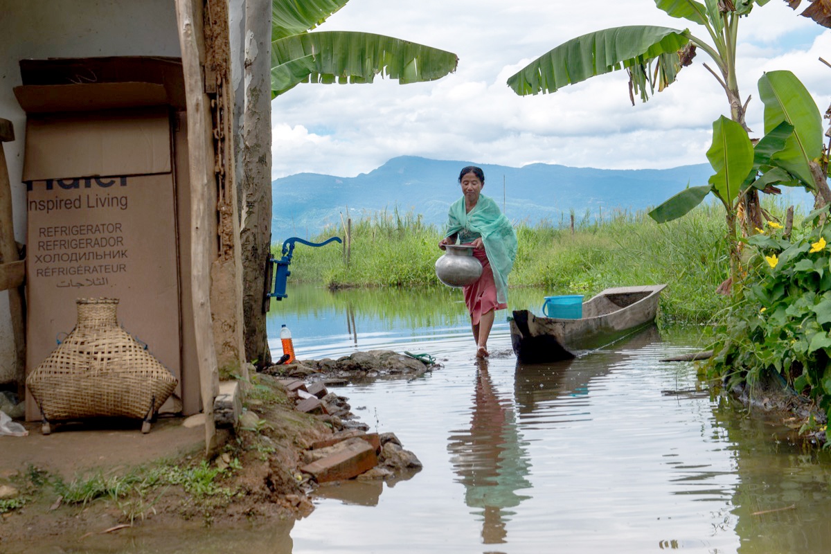  Muktarei Oinam wades through the flooded front yard of her home in the village of Thanga in the Loktak area of Manipur. 